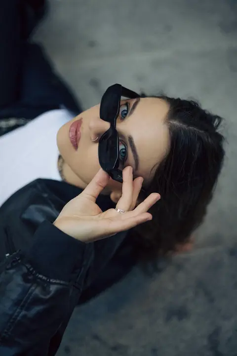 Portrait in sunglasses and a leather jacket lying on pavement
